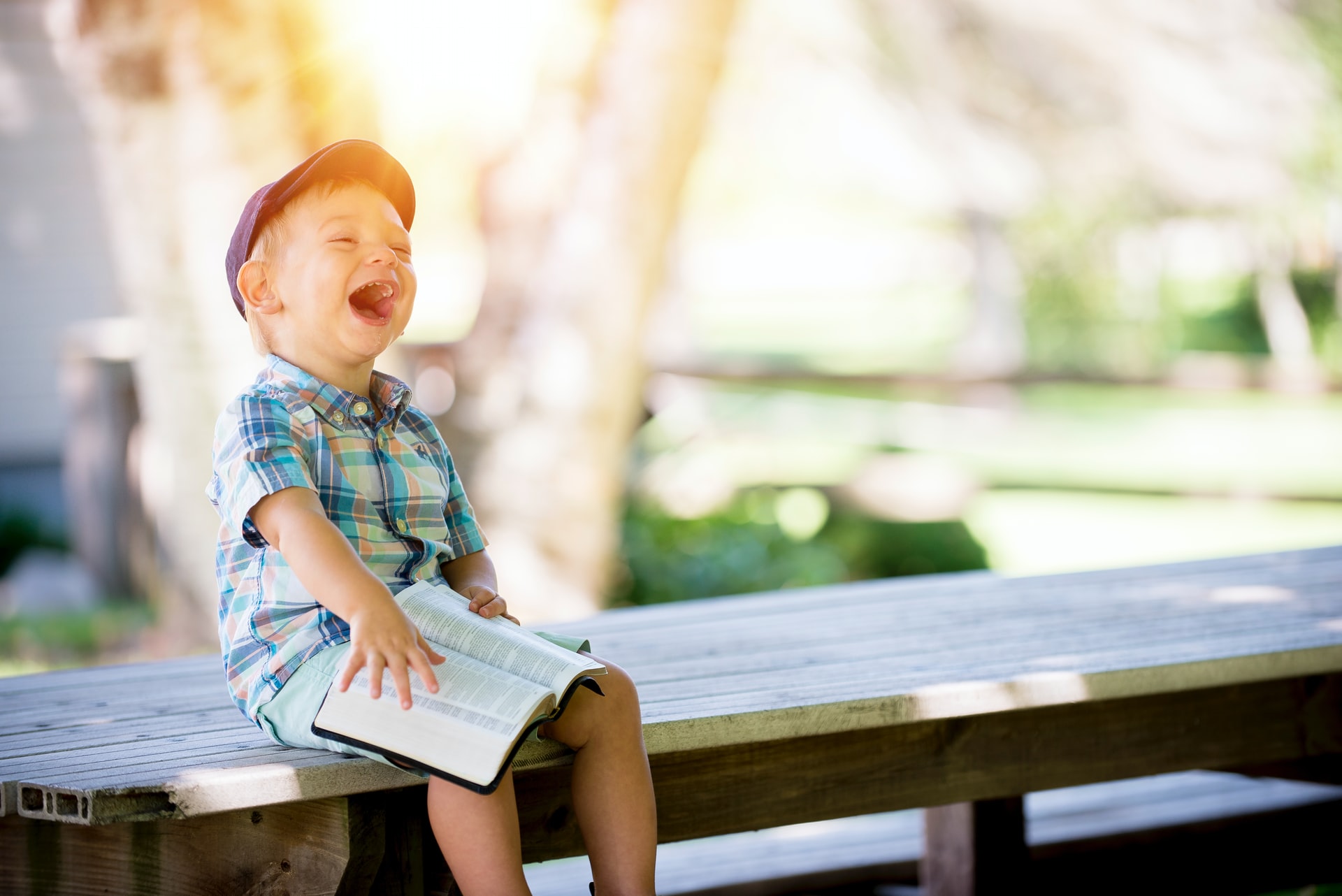 Daily walk in our childlike innocence - image of young boy holding a Bible while laughing.