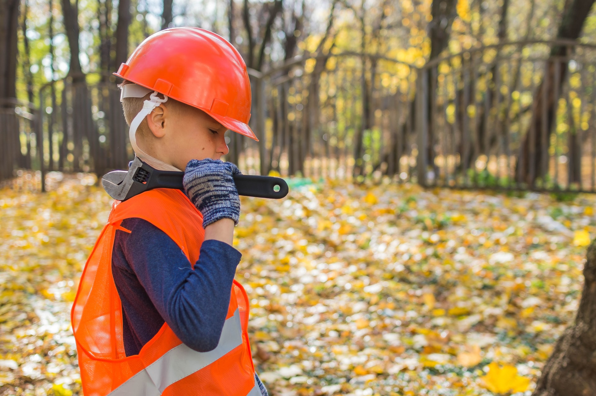 A boy dressed as a man with hardhat and wrench.